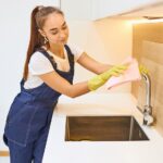 Attractive janitor in working uniform cleaning kitchen